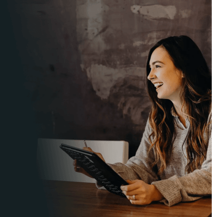Smiling woman using an iPad at a table.